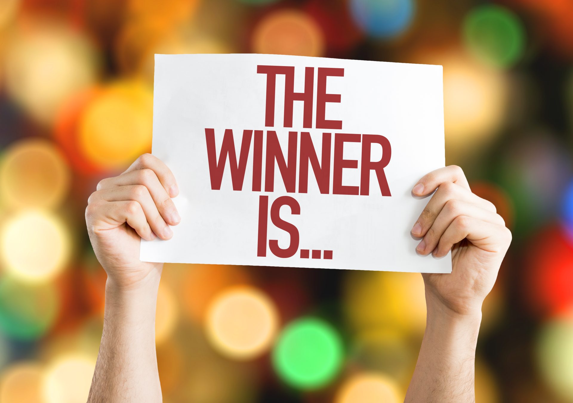 2 Hände mit einem Schild "The Winner is..."
